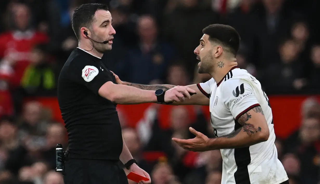 Pemain Fulham, Aleksandar Mitrovic (kanan), mendorong wasit Chris Kavanagh setelah memberikan kartu merah kepada Willian yang menghalau bola menggunakan tangannya untuk mencegah gawang timnya kebobolan dalam babak perempat final Piala FA 2022/2023 melawan Manchester United yang berlangsung di Old Trafford, Minggu (19/3/2023) malam WIB. (AFP/Paul Ellis)
