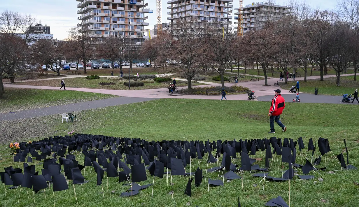 Orang-orang berjalan melewati beberapa ribu bendera kertas hitam yang didirikan oleh aktivis parpol oposisi Koalisi Demokrat, sebagai penghormatan untuk 6.000 orang yang meninggal selama Covid-19 di Bikas Park, Budapest, Hungaria, Rabu (9/12/2020). (ATTILA KISBENEDEK/AFP)