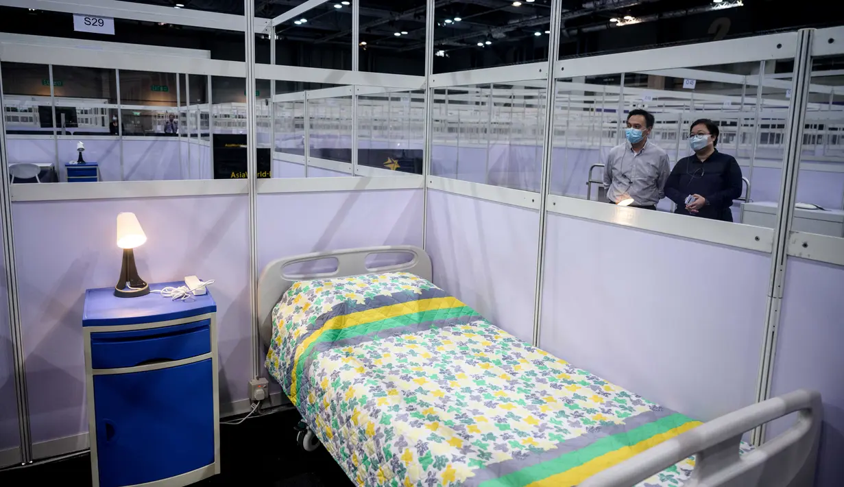 Petugas berdiri di sebelah dinding pemisah antara kamar-kamar yang dipartisi di fasilitas perawatan kesehatan masyarakat di AsiaWorld-Expo di Hong Kong, Selasa (24/11/2020). Rumah sakit darurat khusus corona itu kembali dibuka menyusul lonjakan kasus COVID-19 di Hong Kong. (Anthony WALLACE/AFP)