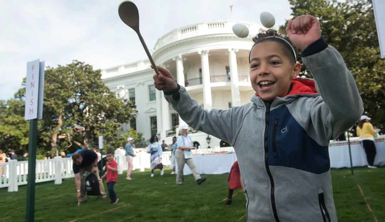 Seorang anak meluapkan kegembiraannya seusai menyelesaikan lomba menggelindingkan telur paskah di Gedung Putih, Washington, Senin (22/4). Acara tahunan itu merupakan bagian dari rangkaian memperingati Paskah yang rutin diselenggarakan Gedung Putih. (Kevin Wolf/AP Images for the American Egg Board)
