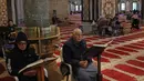 Bangunan berkubah emas ini melindungi Batu Shakhrah, yang diyakini sebagai titik awal perjalanan Nabi Muhammad SAW menuju Sidratul Muntaha dalam peristiwa Isra Miraj. Tampak dalam foto, para pria Palestina membaca Al-Quran di dalam Kubah Batu di kompleks Masjid al-Aqsa, Yerusalem menjelang waktu berbuka puasa selama bulan suci Ramadan 1447 Hijriah pada Rabu 25 Februari 2026. (AHMAD GHARABLI/AFP)