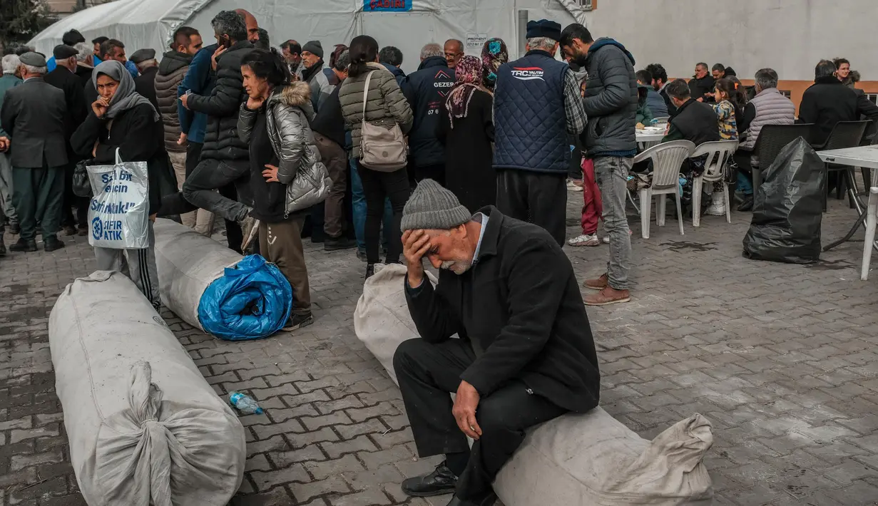 Seorang pria duduk di atas tenda yang digulung di taman Yenimahalle Cemevi, milik anggota komunitas Alevi, Adiyaman, Turki, Minggu (19/2/2023). Gempa bumi berkekuatan 7,8 magnitudo melanda dekat Gaziantep, Turki, pada dini hari tanggal 6 Februari, diikuti oleh gempa susulan berkekuatan 7,5 magnitudo setelah tengah hari. Gempa bumi tersebut menyebabkan kehancuran yang meluas di Turki Selatan dan Suriah Utara dan telah menewaskan lebih dari 40.000 orang. (BULENT KILIC/AFP)