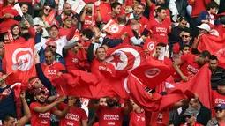 Pendukung Timnas Tunisia mengibarkan bendera dan meneriakan yel-yel saat menyaksikan pertandingan antara Tunisia melawan Libya di kualifikasi Piala Dunia 2018 di Stadion Olimpiade Rades, Tunisia (11/11). (AFP Photo/Fethi Belaid)