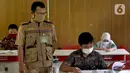 Guru mengawasi murid saat kegiatan Kompetisi Sains Nasional (KSN) seleksi Tingkat SD/ MI se-Kota Depok mata pelajaran IPA di SDN Kemirimuka 3, Depok, jawa Barat, Senin (22/3/2021). Pelaksanaan KSN diikuti perwakilan murid  dari 11 kecamatan di wilayah Depok. (merdeka.com/Arie Basuki)