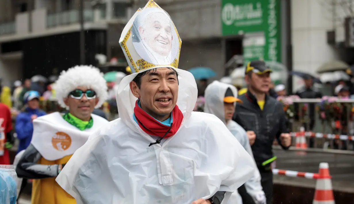 Seorang peserta mengenakan topi bergambar Paus Fransiskus selama mengikuti ajang Tokyo Marathon 2019 di Jepang, Minggu (3/3). Sebagian peserta tampil dengan mengenakan kostum unik seperti tokoh kartun. (AFP Photo/Behrouz Mehri)