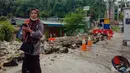 Seorang wanita menggunakan teleponnya di samping dinding yang runtuh setelah gempa magnitudo 5,1 di Jayapura, Provinsi Papua, Indonesia, 9 Februari 2023. Hasil rapat forkopimda menyebutkan Pj Walikota Jayapura menetapkan status tanggap darurat untuk bencana gempa bumi di Kota Jayapura selama 21 hari. (FAISAL NARWAWAN/AFP)