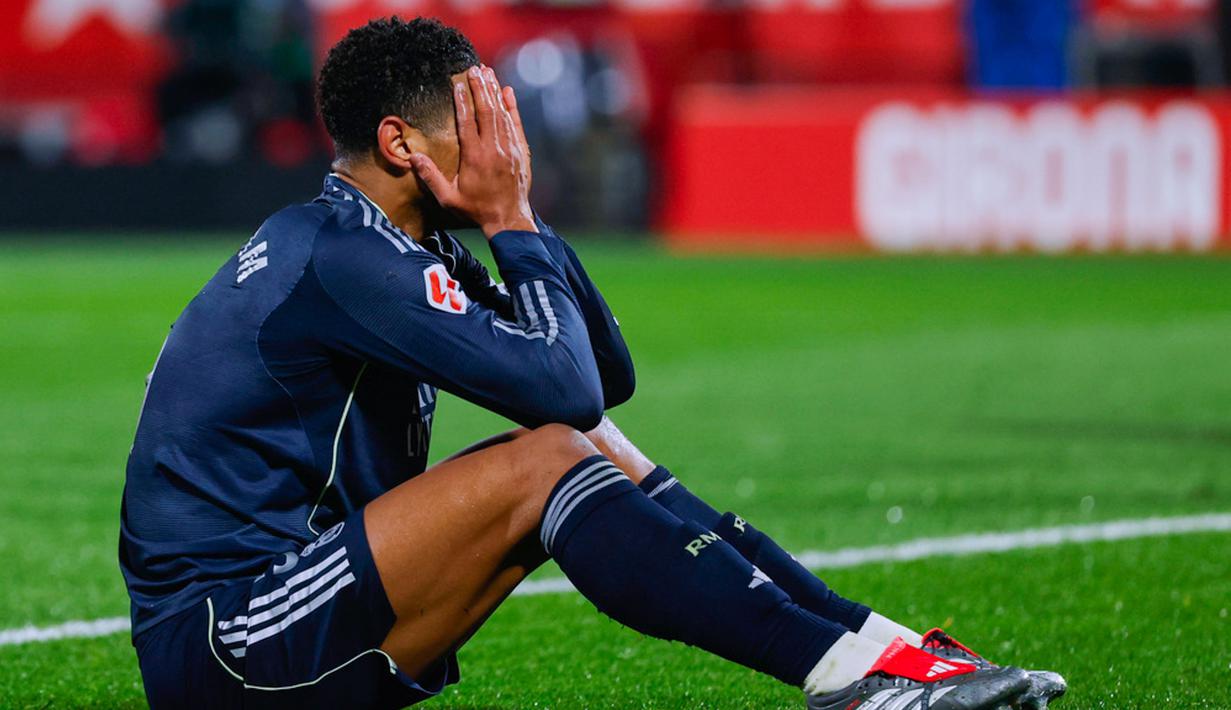 Pemain Real Madrid, Jude Bellingham, menutup wajahnya lantaran kecewa setelah bermain imbang 1-1 ketika menghadapi tuan rumah Girona pada laga lanjutan La Liga 2025/2026 di Montilivi, Senin (1/12/2025) dini hari WIB. (AP Photo/Joan Monfort)