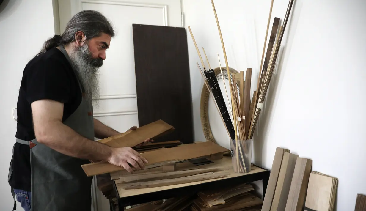Luthier Ali Akbar Soleimani memilih lembaran kayu untuk membuat alat musik petik Iran, di bengkel kerjanya di Teheran pada 28 Januari 2021. Selain sumber penghasilan, pembuatan beragam alat musik tradisional itu juga menjadi salah satu upaya Soleimani untuk melestarikannya. (AP Photo/Vahid Salemi)