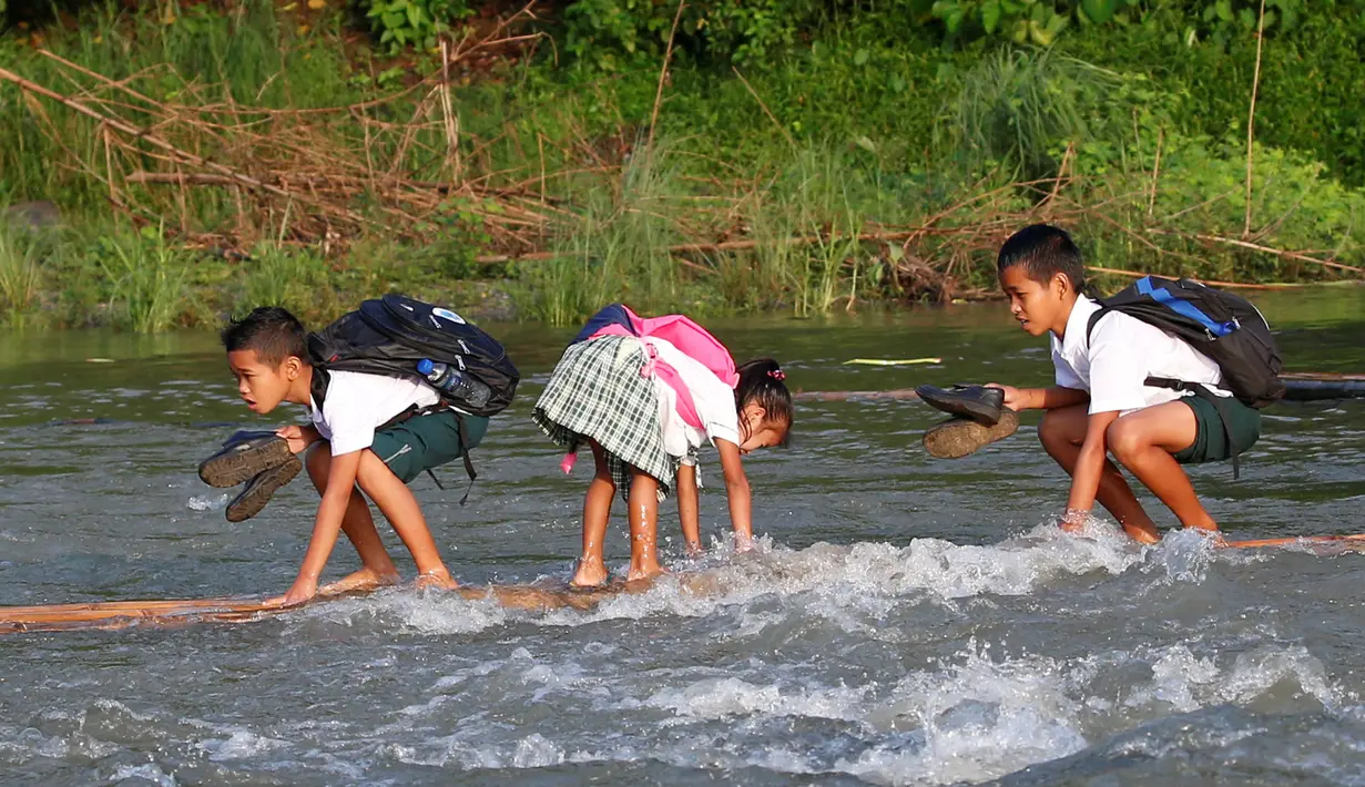 Sejumlah bocah menyeberangi sungai menggunakan perahu rakit untuk berangkat sekolah di Montalban, Rizal timur laut dari Manila, Filipina (13/6). Tidak adanya fasilitas jembatan membuat para siswa mempertaruhkan keselamatannya. (REUTERS/Erik De Castro)