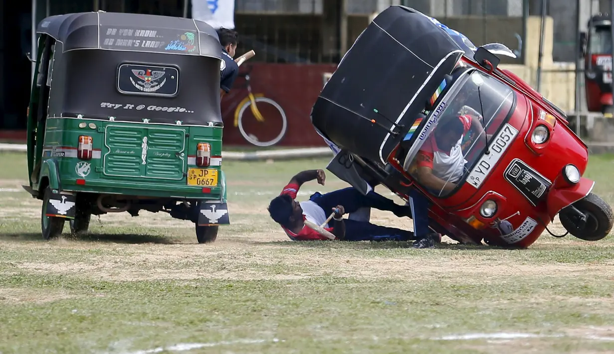 Peserta terjatuh dari bajaj saat bertanding di kompetisi "Tuk Tuk Polo" di Galle, Sri Lanka, (21/2). Olahraga Polo yang biasa mengunakan kuda, hadir di Sri Lanka dengan penampilan unik menggunakan bajaj atau Tuk-tuk. (REUTERS/Dinuka Liyanawatte)