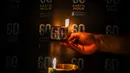 Seorang aktivis menyalakan lilin dalam sebuah acara untuk menandai kampanye lingkungan Earth Hour di Surabaya pada 23 Maret 2024. (JUNI KRISWANTO/AFP)
