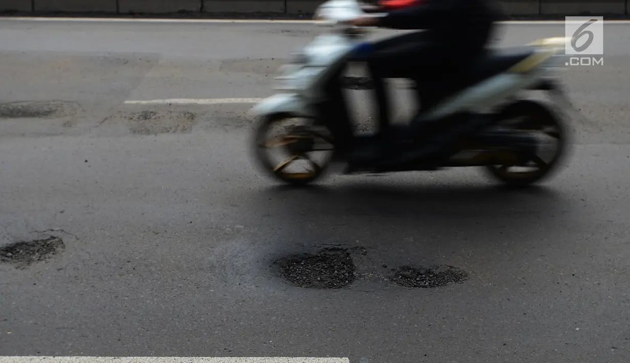 Pengendara motor melintas menghindari jalan berlubang di Jalan Gunung Sahari, Jakarta, Selasa (9/4). Meskipun sudah dilakukan penambalan, jalan raya tersebut sering rusak akibat beban kendaraan yang melintas di atasnya dan intensitas hujan yang belakangan ini cukup tinggi. (merdeka.com/Imam Buhori)