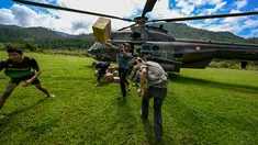 Warga membawa bantuan yang didistribusikan oleh personel TNI AU di wilayah terdampak banjir di Kabupaten Bener Meriah, Provinsi Aceh, pada Kamis 4 Desember 2025. Pendistribusian bantuan logistik bagi masyarakat terdampak banjir bandang di beberapa kabupaten di Aceh, terus dilakukan. (CHAIDEER MAHYUDDIN/AFP)