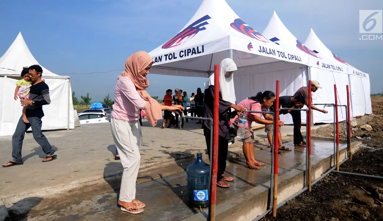Sejumlah pemudik menggunakan kran air di "rest area alternatif" Km 153 Cipali, Jawa Barat, Rabu (21/6). Untuk melepas lelah sebagian pemudik berhenti dan beraktivitas di sejumlah area peristirahatan sementara yang tersedia. (Liputan6.com/Gempur M Surya)