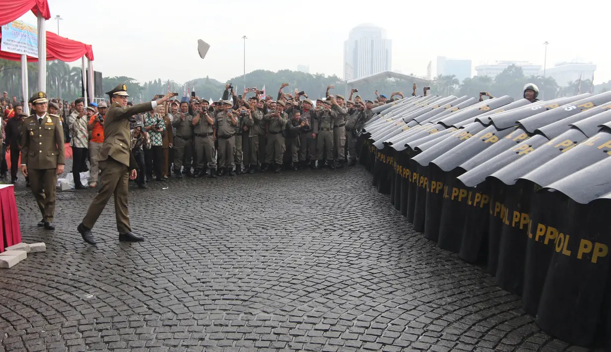 Gubernur DKI Anies Baswedan melemparkan batu dalam simulasi pengamanan untuk berlindung dari personel Satuan Polisi Pamong Praja (Satpol PP) dalam rangka perayan HUT Satpol PP ke-68 di Silang Monas, Jakarta, Kamis (26/4). (Liputan6.com/Arya Manggala)