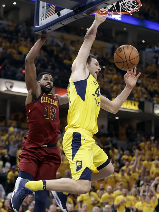 Pemain Pacers, Bojan Bogdanovic (kanan) melakukan dunks melewati adangan pemain Cavaliers, Tristan Thompson (13) pada game keenam playoffs NBA basketball di Bankers Life Fieldhouse, Indianapolis, (27/4/2018). Pacers menang 121-87. (AP/Darron Cummings)