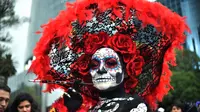 Seorang wanita berpakaian seperti "Catrina" ambil bagian dalam parade catrinas atau Hari Orang Mati di Reforma Avenue, Mexico City, 21 Oktober 2018. Hari kematian ini merupakan tradisi Halloween ala warga Hispanik di Meksiko. (RODRIGO ARANGUA/AFP)