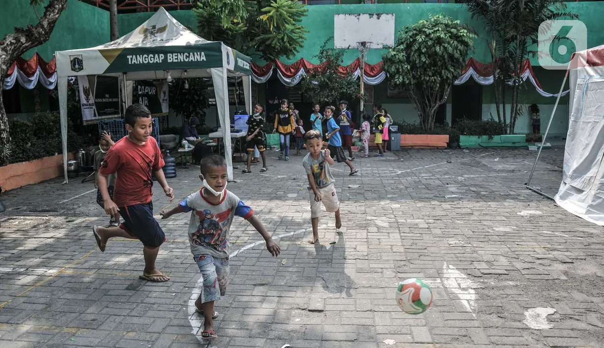 Anak-anak korban kebakaran saat bermain di lapangan sekolah SDN 09 Kebon Kosong, Kemayoran, Jakarta, Selasa (31/8/2021). Ratusan pengungsi ditempatkan di dua ruang kelas yang dipisahkan berdasarkan jenis kelamin. (merdeka.com/Iqbal S. Nugroho)