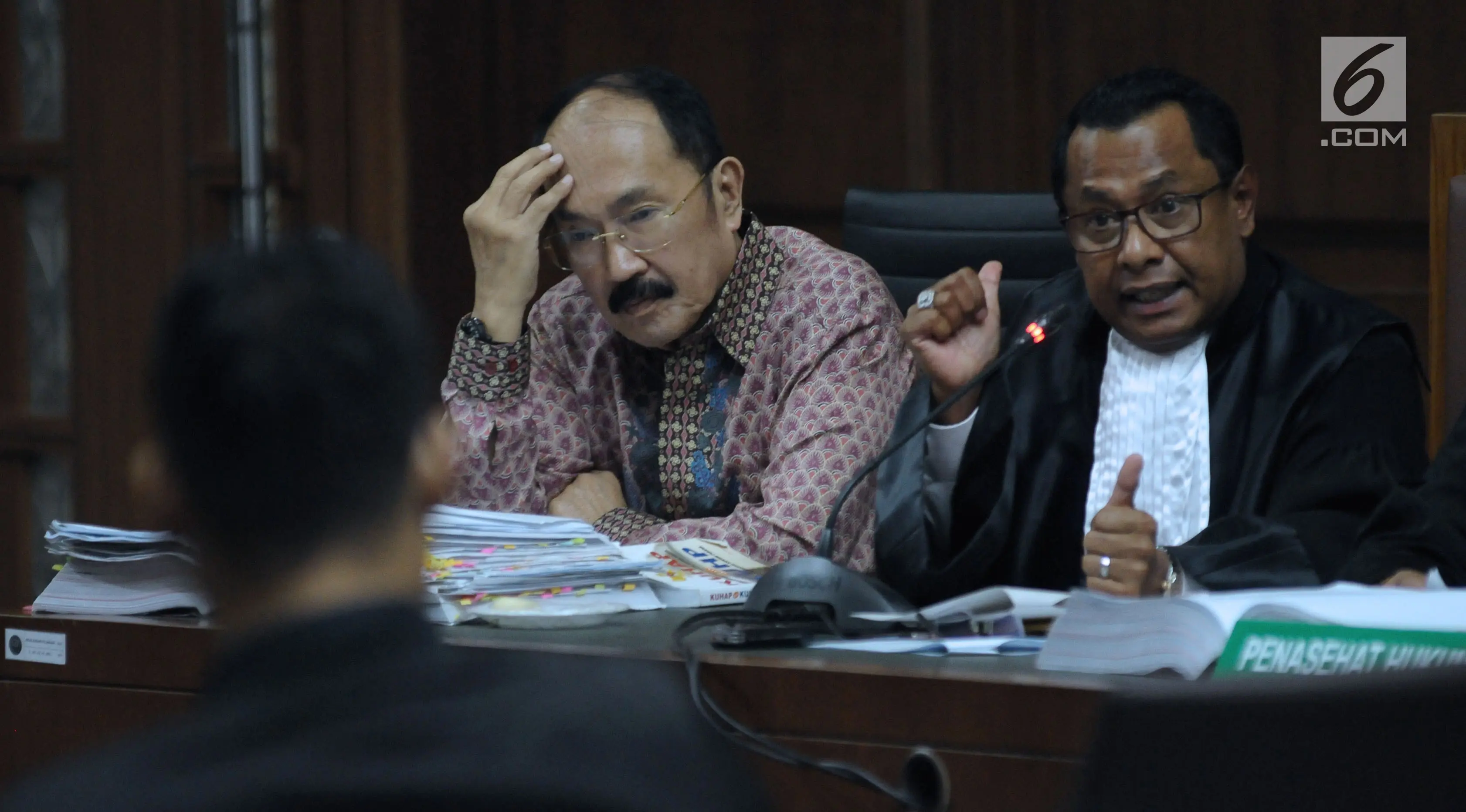 Terdakwa kasus merintangi penyidikan dugaan korupsi e-KTP, Fredrich Yunadi (kiri) menymak keterangan stafnya pada sidang lanjutan di Pengadilan Tipikor, Jakarta, Kamis (12/4). Sidang mendengar keterangan saksi. (Liputan6.com/Helmi Fithriansyah)