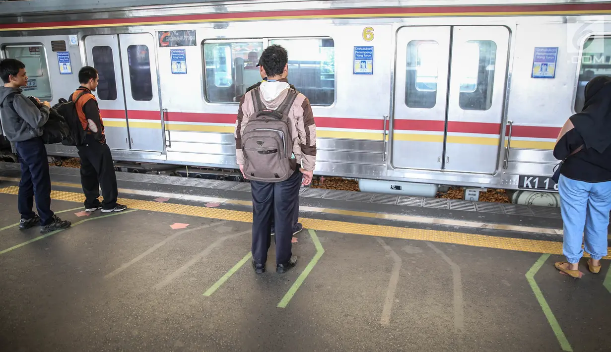 Penumpang berdiri di garis antrean penumpang di Stasiun Juanda, Jakarta, Kamis (10/8). PT KAI Commuter Jabodetabek melakukan uji coba garis antrean penumpang tersebut guna untuk keselamatan bagi para penumpang. (Liputan6.com/Faizal Fanani)