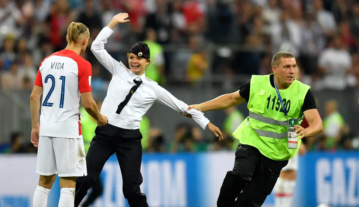 Seorang wanita menyusup masuk ke lapangan dalam laga final Piala Dunia 2018 antara Prancis dan Kroasia di Luzhniki Stadium, Minggu (15/7). Empat orang berseragam polisi menyusup masuk ke dalam lapangan. (AP/Martin Meissner)
