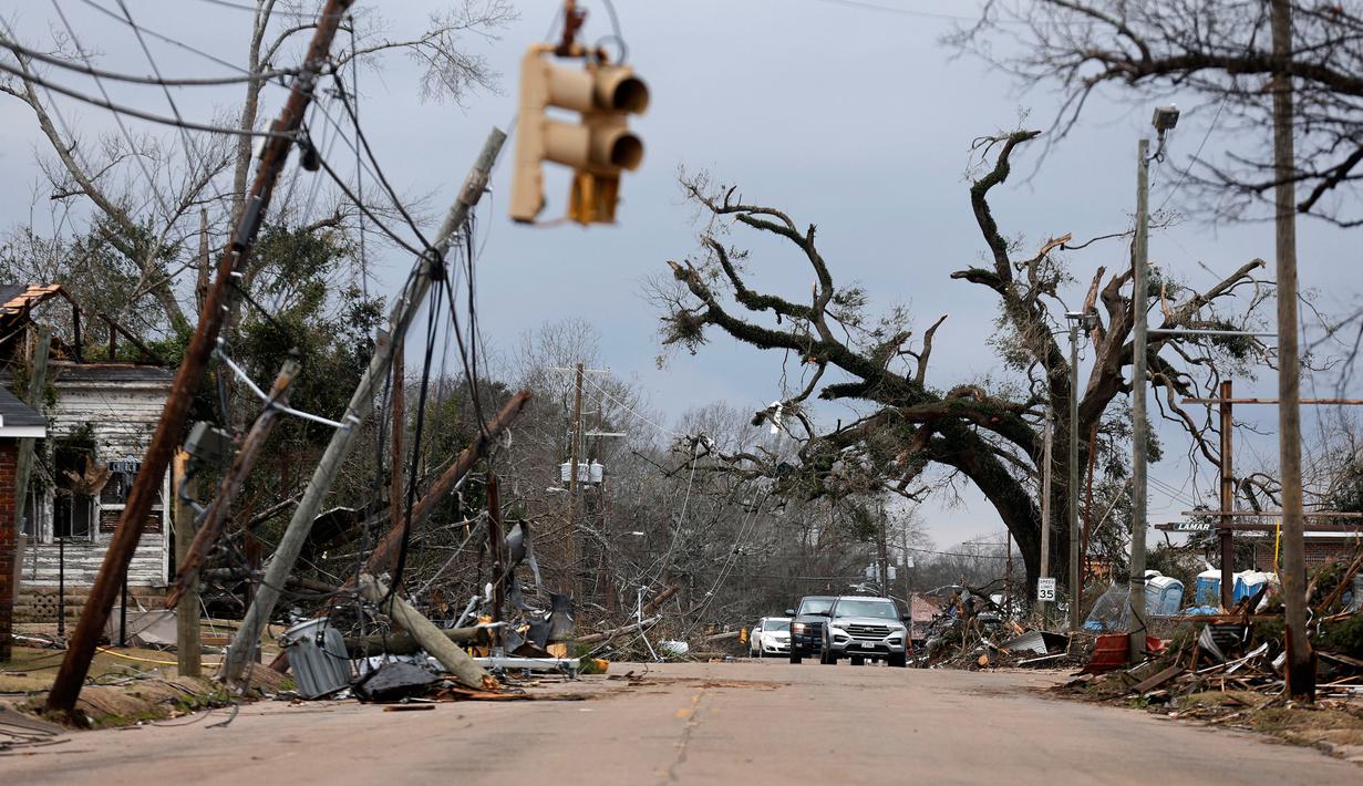 Mobil melewati pepohonan dan kabel listrik yang tumbang setelah tornado di Chestnut Blvd, Selma, Alabama, Amerika Serikat, 13 Januari 2023. Badai menyebabkan pemadaman listrik yang berdampak terhadap ribuan orang di empat negara bagian. (AP Photo/Stew Milne)