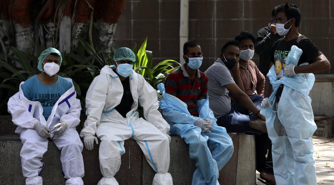 Petugas kesehatan beristirahat saat sela-sela mengkremasi korban COVID-19 di New Delhi, India, Senin (19/4/2021). New Delhi memberlakukan lockdown selama seminggu untuk mencegah runtuhnya sistem kesehatan di tengah ledakan kasus COVID-19. (AP Photo/Manish Swarup)