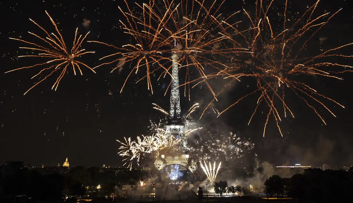 <p>Kembang api menerangi Menara Eiffel selama perayaan Hari Bastille di Paris, Kamis (14/7/2022) malam. Sebagai informasi, perayaan Hari Bastille diwarnai dengan parade besar militer dan pesta kembang api. (AP Photo/Lewis Joly)</p>