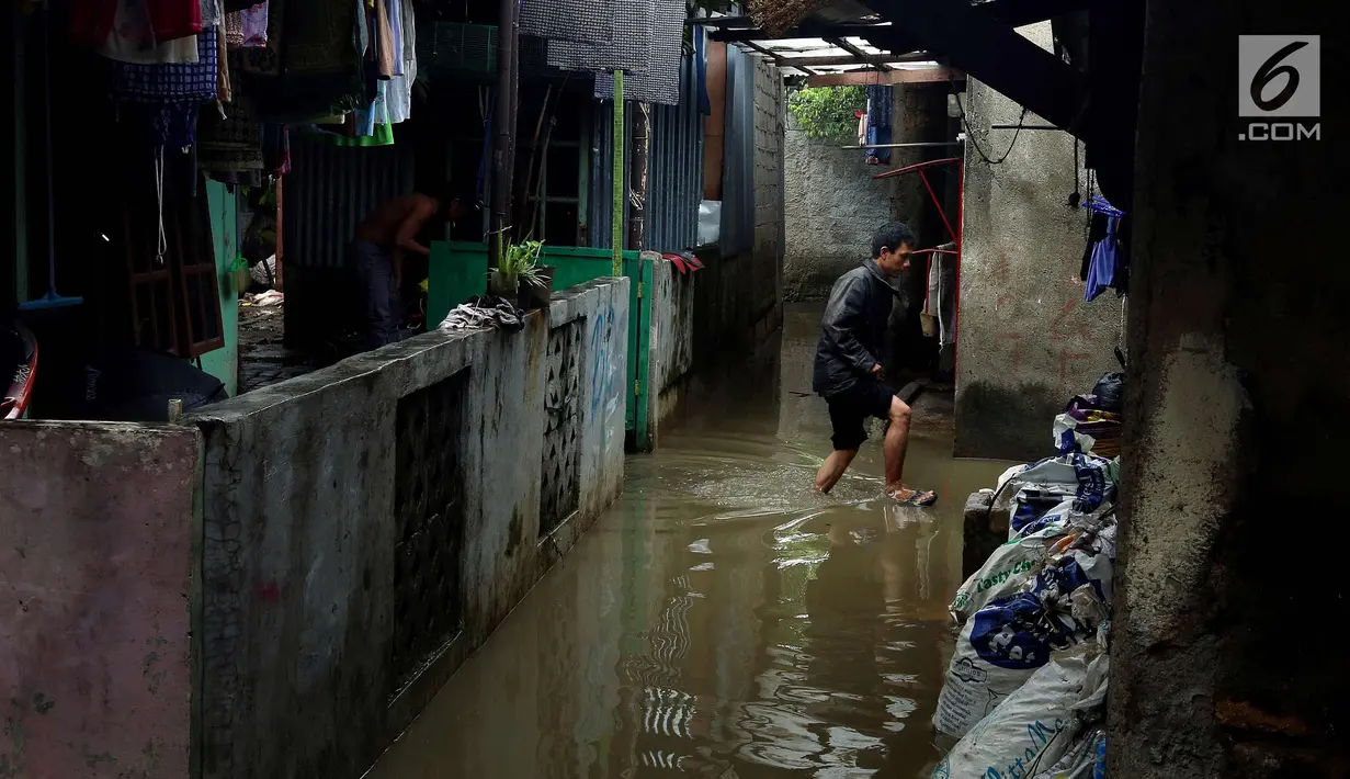 Warga melintasi banjir di permukiman Jati Padang, Jakarta, Kamis (30/11). Banjir yang terjadi tersebut akibat tanggul darurat di Kali Pulo jebol karena genangan air yang cukup deras dan membanjiri permukiman sekitar. (Liputan6.com/Johan Tallo)