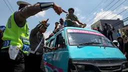 Polisi berjaga saat sopir angkutan konvensional demo transportasi online di Jalan Urip Sumoharjo, Makassar, Rabu (1/11). Para pendemo gagal menemui Gubernur Sulsel yang menyebabkan para pendemo mengamuk. (AFP Photo/Yusuf Wahil)