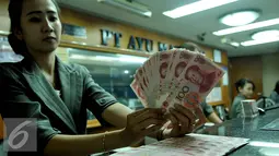Petugas menunjukkan uang pecahan 100 Yuan di tempat penukaran uang, Jakarta, Kamis (13/8/2015). Kebijakan Tiongkok yang sengaja melemahkan (devaluasi) mata uang Yuan membuat Rupiah melemah terhadap dolar AS. (Liputan6.com/Johan Tallo)