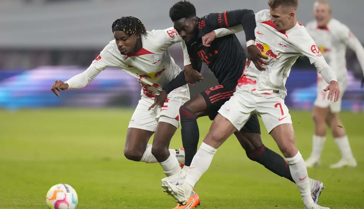 Gelandang Bayern Munchen Alphonso Davies berebut bola dengan bek RB Leipzig Mohamed Simakan pada laga pekan ke-16 Bundesliga Jerman 2022-2023 di Red Bull Arena, Sabtu (21/1/2023) dini hari WIB. Bayern Munchen berbagi poin saat bertandang ke markas RB Leipzig. (AP Photo/Matthias Schrader)