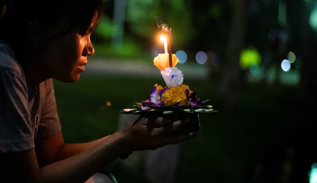 Seorang wanita berdoa sebelum menghayutkan 'krathong' untuk merayakan festival Loy Krathong di sebuah danau di Bangkok, Kamis (22/11). Loy Krathong dirayakan setiap tahun di seluruh Thailand sebagai penghormatan kepada dewi air. (Jewel SAMAD/AFP)