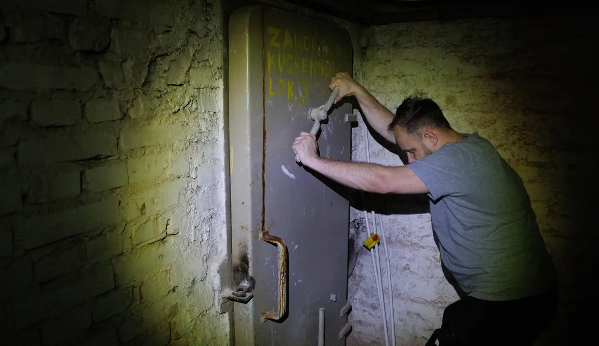 Warga setempat, Jacek (37), menutup pintu ke tempat perlindungan di ruang bawah tanah sebuah bangunan perumahan di Warsawa, Polandia, 19 Oktober 2022. Pertempuran di sekitar pembangkit listrik tenaga nuklir Ukraina dan ancaman Rusia untuk menggunakan senjata nuklir telah membangkitkan kembali ketakutan Eropa akan nuklir. (AP Photo/Michal Dyjuk)