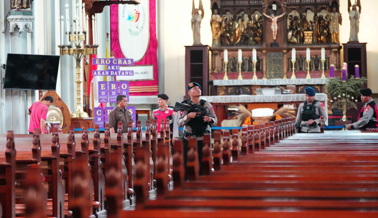 Polisi dari berbagai unsur melakukan sterilisasi di Katedral Bunda Maria Diangkat ke Surga atau Gereja Katedral Jakarta, Selasa (23/12/2025). Tampak dalam foto, personel dari regu penjinak bom kepolisian Indonesia memeriksa deretan kursi di dalam gereja selama operasi keamanan menjelang perayaan Natal di Katedral Bunda Maria Diangkat ke Surga atau Gereja Katedral Jakarta, Selasa 23 Desember 2025. (AP Photo/Tatan Syuflana)