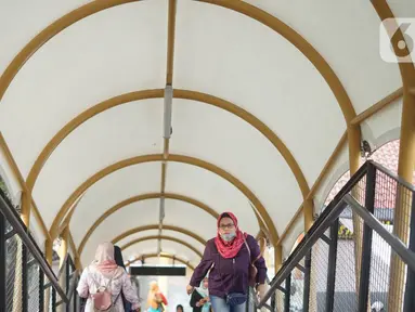 Warga melitasi Jembatan Penyeberangan Orang (JPO) di depan Stasiun Pasar Minggu, Jakarta, Kamis (9/1/2020). JPO yang juga dilengkapi dengan penutup dan lampu warna-warni tersebut menghubungkan Stasiun Pasar Minggu dengan pasar tradisional Pasar Minggu. (Liputan6.com/Immanuel Antonius)