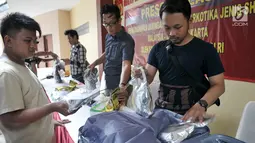 Petugas membongkar barang bukti kasus peredaran narkotika jenis sabu jaringan Malaysia dalam jumpa pers di Rumah Sakit Polri, Selasa (13/6). Modus operandi dalam mengedarkan narkoba ini dengan dikamuflase di dalam koper. (Liputan6.com/Yoppy Renato)