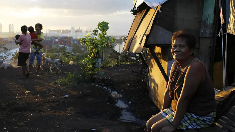 Juanita Espinosa duduk dan menikmati matahari terbenam di depan rumahnya di perkampungan Smokey Mountain di Manila, Filipina (AP)