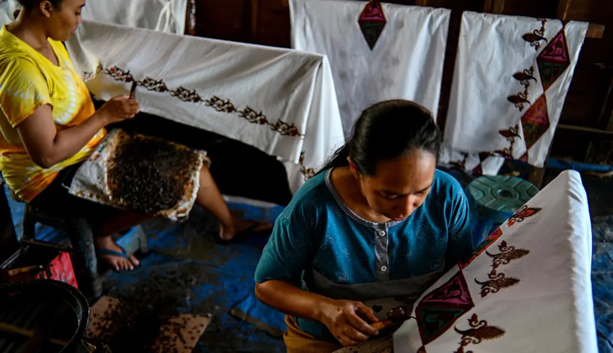 Para pekerja membuat desain batik di sebuah bengkel di Banda Aceh, Aceh, Rabu (13/10/2021). Batik Aceh memiliki ciri khas tersendiri, yaitu menggunakan perpaduan unsur alam dan budaya dari masyarakat Aceh sendiri. (Chaideer MAHYUDDIN/AFP)
