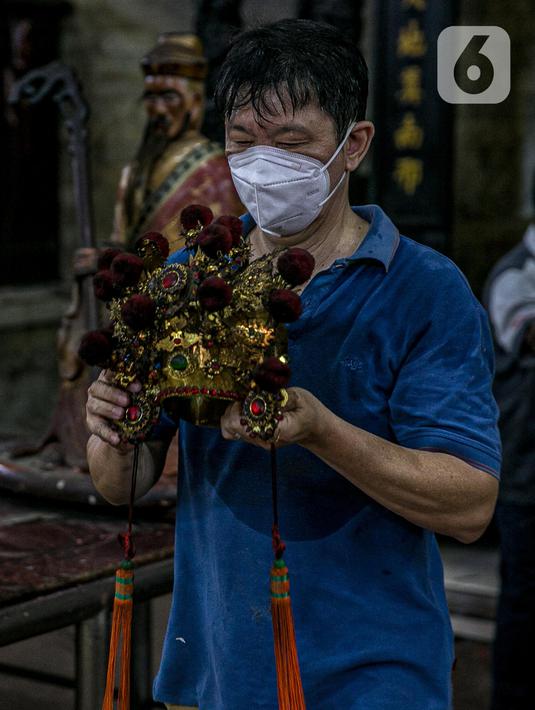 Seorang jemaat memindahkan patung yang ada di Vihara Amurva Bhumi, Jakarta, Kamis (4/2/2021). Ritual mencuci patung dewa serta bersih-bersih ini dilakukan dalam rangka menyambut perayaan Tahun Baru Imlek 2572. (Liputan6.com/Faizal Fanani)