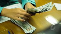 Petugas menghitung mata uang AS di penukaran valas Ayu Masagung, Jakarta, Senin (9/3/2015). Pada awal perdagangan rupiah dibuka pada level 12.994 atau melemah 18 poin dibanding penutupan akhir pekan lalu di posisi 12.976. (Liputan6.com/Faizal Fanani)