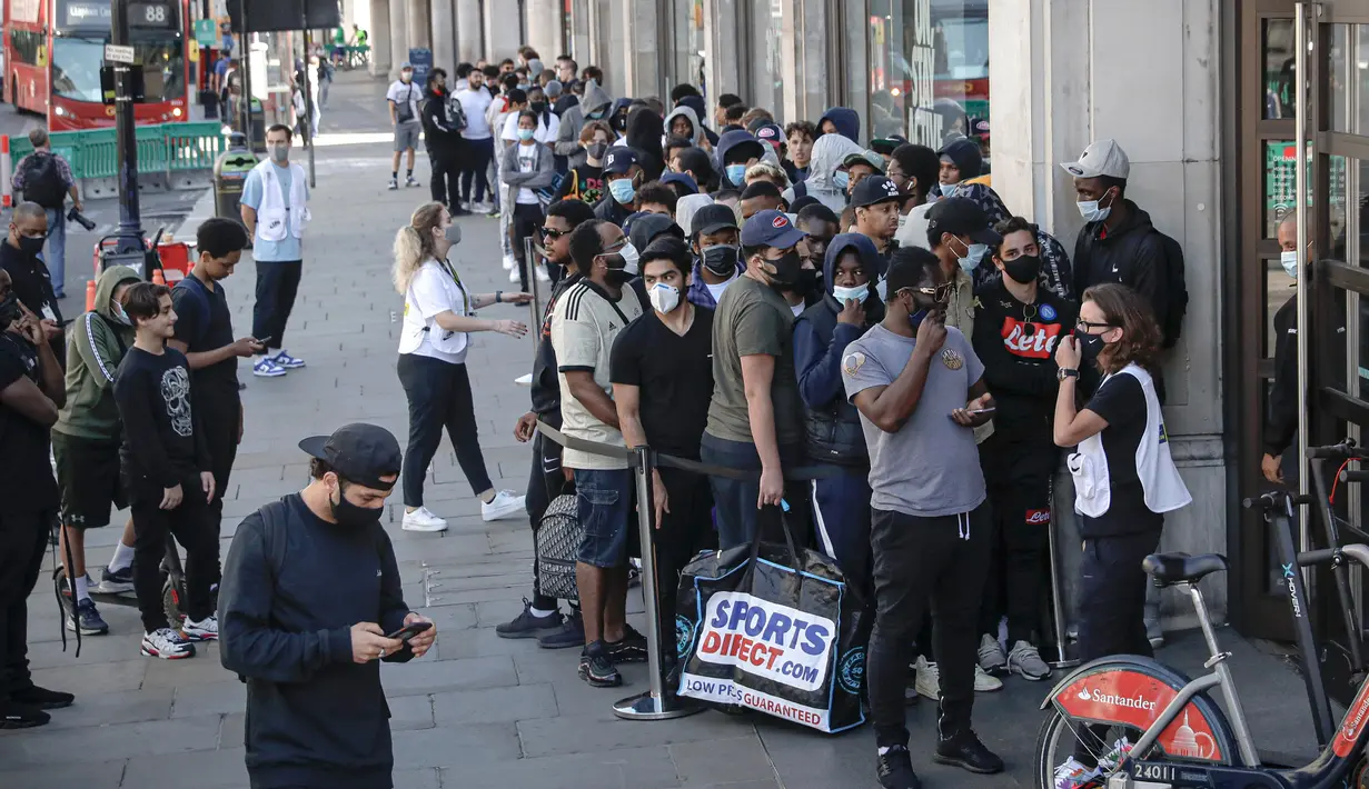 Karyawan Nike meminta orang-orang yang antre untuk menjaga jarak di luar toko Niketown di London, Senin (15/6/2020). Antrean panjang terjadi di luar toko-toko yang berada di sejumlah kota di Inggris saat negara itu melakukan pelonggaran lockdown dan mulai membuka pusat perbelanjaan. (AP/Matt Dunham)