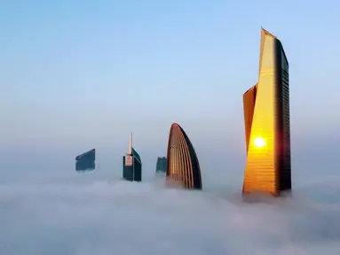 Foto udara memperlihatkan pemandangan Al Hamra Tower (kanan), Kantor Pusat Bank Nasional Kuwait, dan Al Rayah Tower (kiri kedua) di tengah kabut tebal, Kuwait City, 21 Januari 2023. Al Hamra Tower adalah gedung tertinggi ke-23 di dunia dan tergolong bangunan baru di Kuwait City. (YASSER AL-ZAYYAT/AFP)