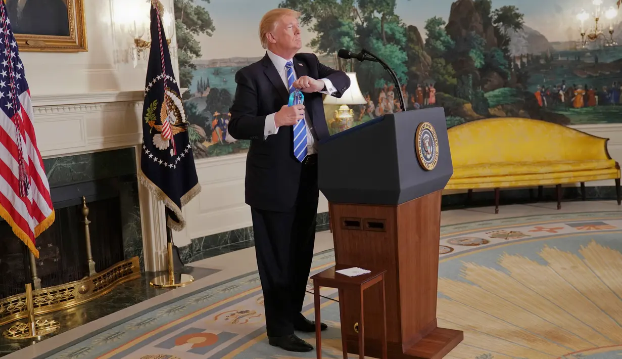 Presiden AS, Donald Trump membuka botol air mineral disela pidatonya di Ruang Diplomatik, Gedung Putih, Rabu (15/11). Trump yang awalnya gagal menemukan botol mineralnya, diberitahu seorang wartawan letak air minum tersebut. (AP/Pablo Martinez Monsivais)
