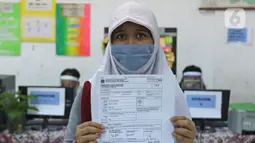 Calon siswa menunjukkan tanda bukti lapor diri usai pengurusan Penerimaan Peserta Didik Baru (PPDB) di SMPN 60 Jakarta, Rabu (17/6/2020). Sejumlah sekolah di DKI Jakarta, salah satunya SMPN 60 Jakarta, membuka penerimaan peserta didik baru sejak 15 Juni 2020. (Liputan6.com/Herman Zakharia)