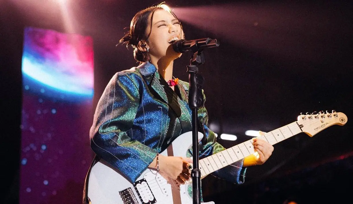 Tampil dengan gitar putih, aksi panggung Ziva Magnolya satu ini sukses mencuri perhatian netizen. Dirinya terlihat memakai makeup yang cukup simpel serta tatanan rambut sederhana namun tetap memesona. (Liputan6.com/IG/@zivamagnolya)