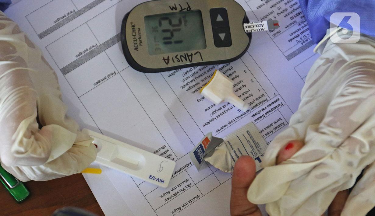 Tenaga kesehatan melakukan rapid tes kepada di MTs As-Syafiiyah, Cilangkap, Jakarta, Kamis (3/6/2021). Vaksinasi massal di zona merah RT 03/RW 03 Cilangkap akibat klaster halal bi halal dilakukan terhadap warga yang telah menjalani tes usap dengan hasil negatif. (Liputan6.com/Herman Zakharia)