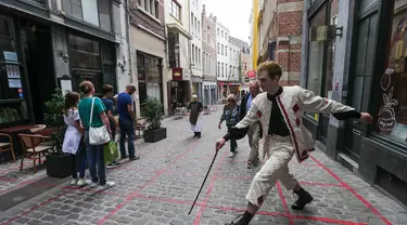 Seorang seniman memainkan permainan dalam garis persegi (grid game) dengan pelintas di Royal Gallery of Saint Hubert di Brussel, Belgia (15/7/2020). Permainan ini dirancang agar orang menghormati aturan jaga jarak sosial selama pandemi COVID-19. (Xinhua/Zheng Huansong)
