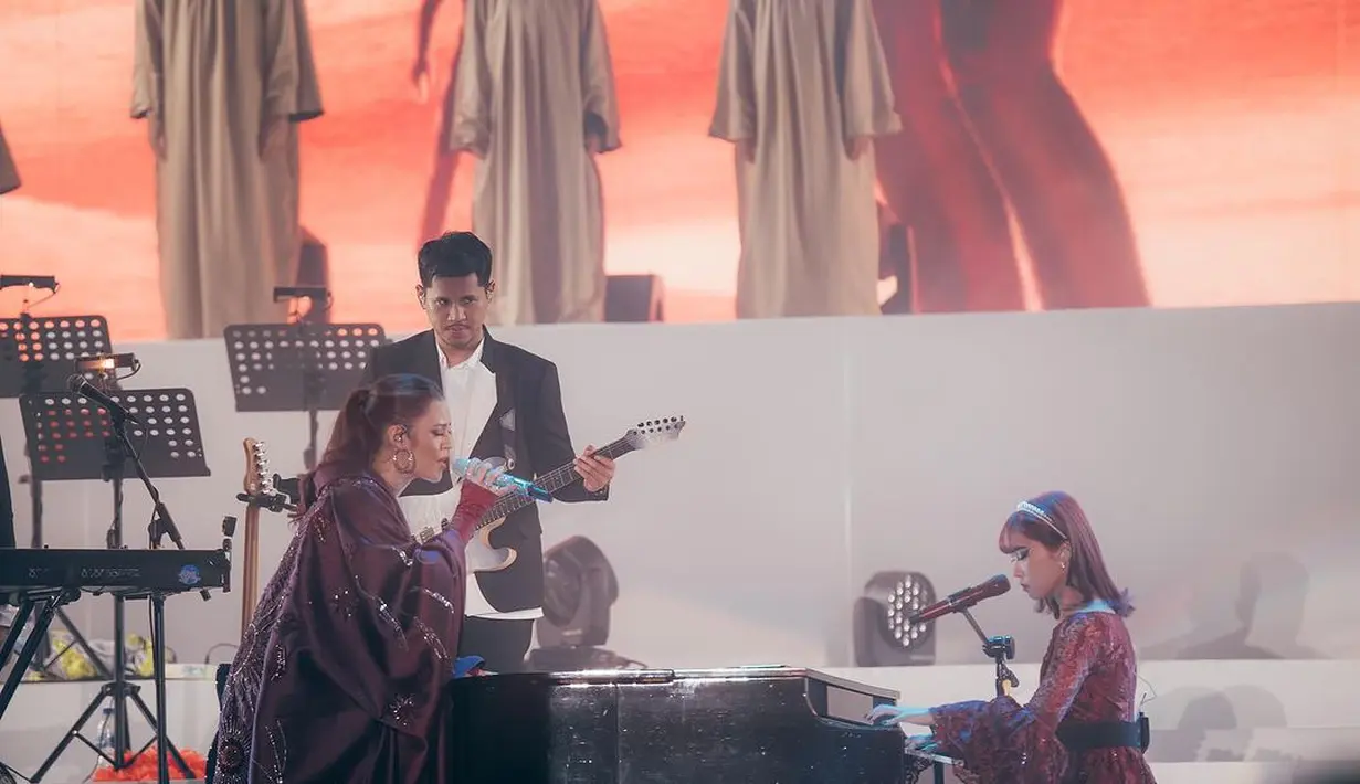 Seperti pada saat Isyana bermain piano dengan dress merah brukat. Raisa pilih tampil dengan dress jubah burgundy full payet [@raisa6690]