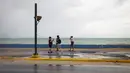Sekelompok wisatawan berjalan di dekat laut sebelum kedatangan Badai Tropis Fiona di San Juan, Puerto Rico, Sabtu (17/9/2022). Setelah dari Puerto Rico, Fiona diproyeksikan melintasi Republik Dominika pada Senin mendatang dengan ancaman hujan deras yang berpotensi memicu banjir bandang atau longsor. (AP Photo/Alejandro Granadillo)